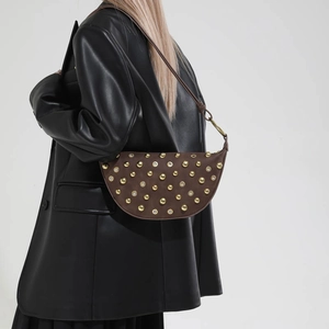 Detail of brown half-moon underarm bag with gold rivets and eyelets on suede leather