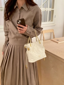 Détail du sac seau matelassé blanc avec bandoulière chaîne dorée et fermeture cordon