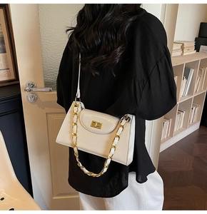 Détail du sac à bandoulière en cuir texturé blanc crème avec garniture dorée sur un modèle
