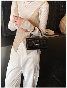 Detailed view of crocodile embossed leather texture and silver lock on a black handbag