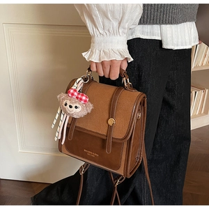 Detail of vintage patchwork backpack with metal buckle and plush bear charm accent