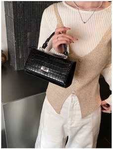 Chic black crocodile embossed handbag carried by model for an elegant vintage outfit