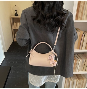 Bolso de media luna rosa con colgante de poni, mostrado en una escena interior chic
