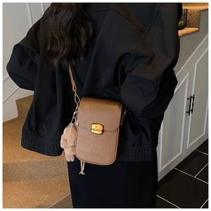 Detailed view of brown leather crossbody bag with vintage texture and plush bear charm