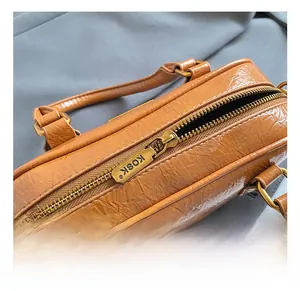 Detailed close-up of premium gold hardware and brand zipper on brown leather handbag
