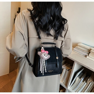 Detailed back view of vintage black backpack with plush charm and golden buckle closure