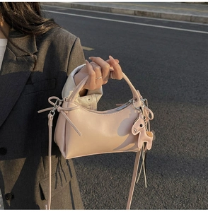 Vista detallada del bolso hobo de cuero rosa con dije de caballo sobre blazer gris