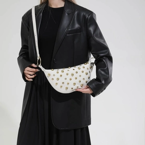 Detail of white leather crescent bag with rows of polished gold spherical studs