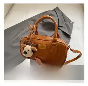 Detail of vintage brown leather bowling bag with gold nameplate and cute dog charm