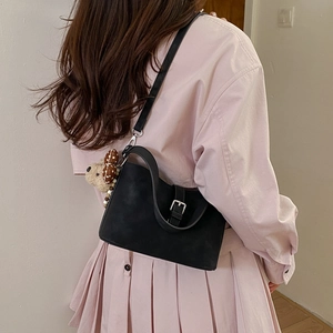 Detail of black suede shoulder bag with silver buckle and cute plush bear charm