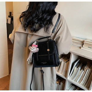 Detail showing vintage black PU leather flap backpack with golden logo and plush charm
