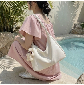 White leather shoulder bag detail with cute plush bear charm and decorative strap knot