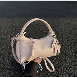 Detalle de bolso de media luna rosa con colgante de poni de cuero y correa ajustable