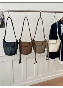 Dettaglio di borse a secchiello minimaliste in nero, marrone e beige con trama in pelle