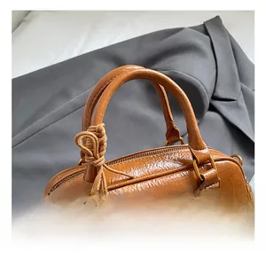 Close-up of brown polished leather bowling bag with vintage texture and golden logo tag