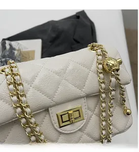 Detailed close-up of white quilted leather bag with gold ball charm and metal chain
