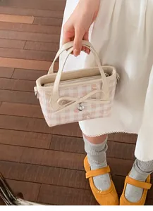 Close-up of pink checkered canvas bag with bow and heart pendant on a wooden floor