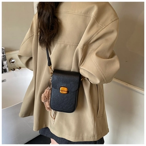 Detailed side view of a black retro crossbody phone bag with gold clasp and plush bear charm