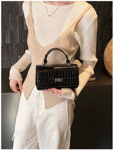 Detail shot of black crocodile pattern leather handbag with vintage metal rotating lock