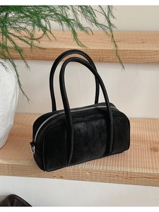 Dettaglio di una borsa a mano Boston nera in pelle con manici lunghi su scalini di legno