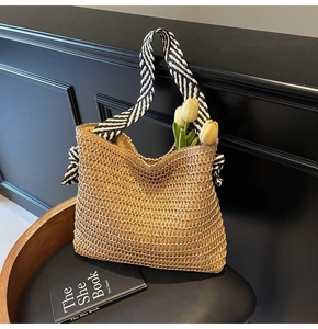 Detail of woven straw tote bag featuring striped ribbon handles and bow decoration
