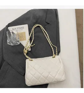 Close-up of white quilted leather texture with gold ball chain on a grey blazer