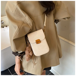 Chic cream textured leather phone crossbody bag with gold buckle and plush charm on model