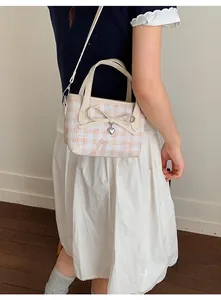 Detail of pink plaid bag showing large bow, heart pendant, and sweet cartoon prints