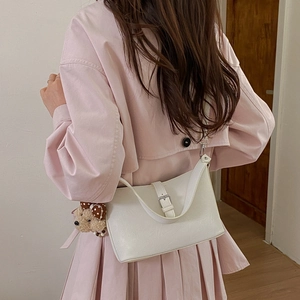 Detail view of white pebbled leather handbag with cute teddy bear plush charm accessory