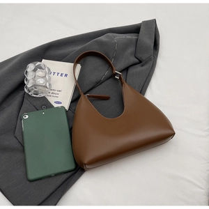 Détail du sac à bandoulière marron en demi-lune avec boucle argentée et cuir synthétique
