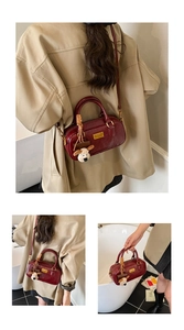Detail view of burgundy leather bowling bag with gold nameplate and plush dog charm