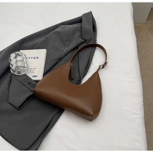Détail du sac bandoulière croissant en cuir PU marron avec boucle argentée sur blazer