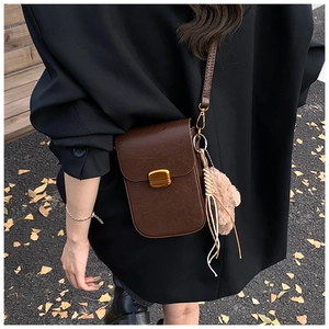 Close-up of vintage brown pebble leather crossbody phone bag with gold clasp and bear charm