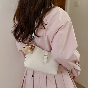 Detail of white PU leather shoulder bag with silver buckle and cute plush bear pendant