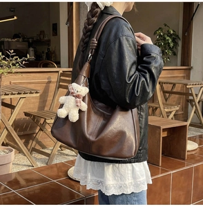 Detail of vintage brown tote bag with leather texture and cute plush bear accessory