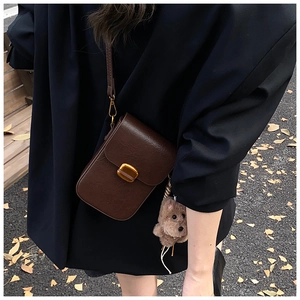 Detail showing vintage brown leather phone bag with gold metal clasp and dog charm