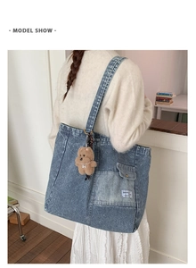 Detail shot of blue striped denim tote bag with external pocket and small brown bear charm