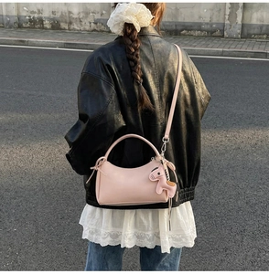 Bolso rosa de piel con colgante de caballo mostrado en un look de estilo urbano