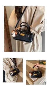 Detail of a black patent leather bowling bag with gold hardware and a cute dog charm