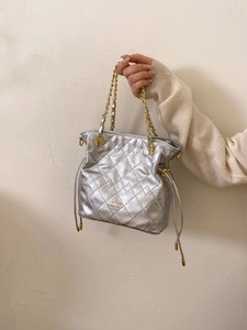 Détail du sac seau matelassé argenté avec chaîne dorée et logo Pan'tor London gravé