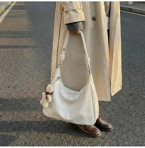 Detail of white large capacity tote bag with soft leather texture and plush bear pendant