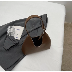 Détail d'un sac hobo marron avec fermeture éclair argentée dans un décor urbain chic