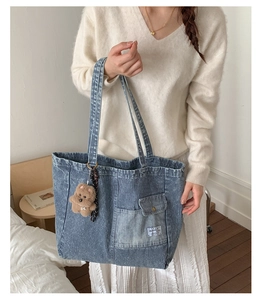 Detail view of denim tote bag with vertical stripes and a cute brown plush bear charm