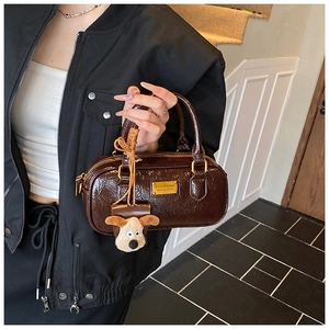 Detail of vintage brown leather bowling bag with gold hardware and plush dog pendant