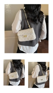 Detailed view of white quilted crossbody bag with gold chain strap on a female model
