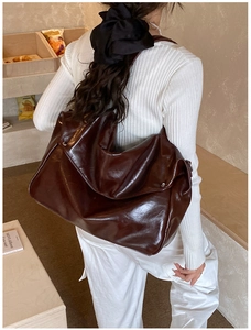 Detailed view of dark brown oil-leather tote bag with side metal rivet decorations