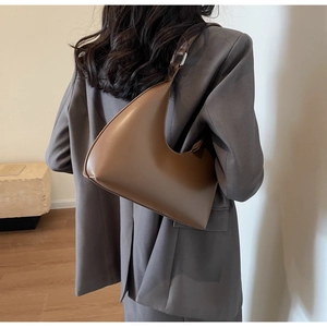 Sac hobo croissant en cuir marron avec bandoulière réglable porté par un modèle