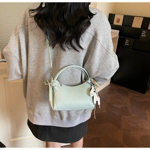 Detalle del bolso verde menta con lazo y colgante de caballo llevado por una modelo