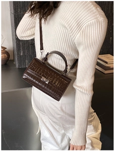 Detail shot of a dark brown crocodile embossed crossbody bag with silver twist lock and strap