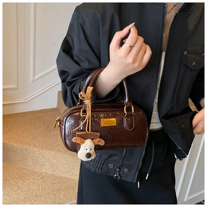 Close-up of vintage brown bowling shoulder bag with glossy finish and plush puppy charm